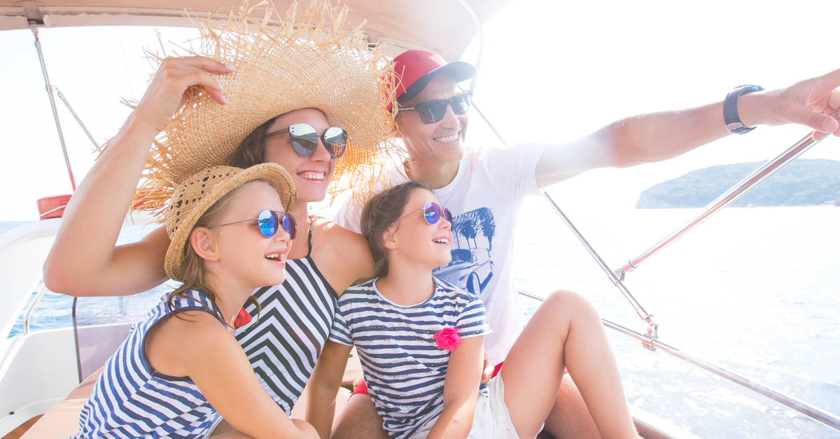 atxpartyboats-297272-protect-sunburn-boat-blogbanner1 A family of four is sitting on a boat. They're relaxing under the canopy, protected from the sun with hats and sunglasses.