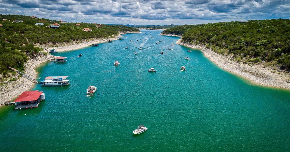 An aerial view of a channel on Lake Travis in Austin, Texas, on a partly cloudy day with numerous boats.